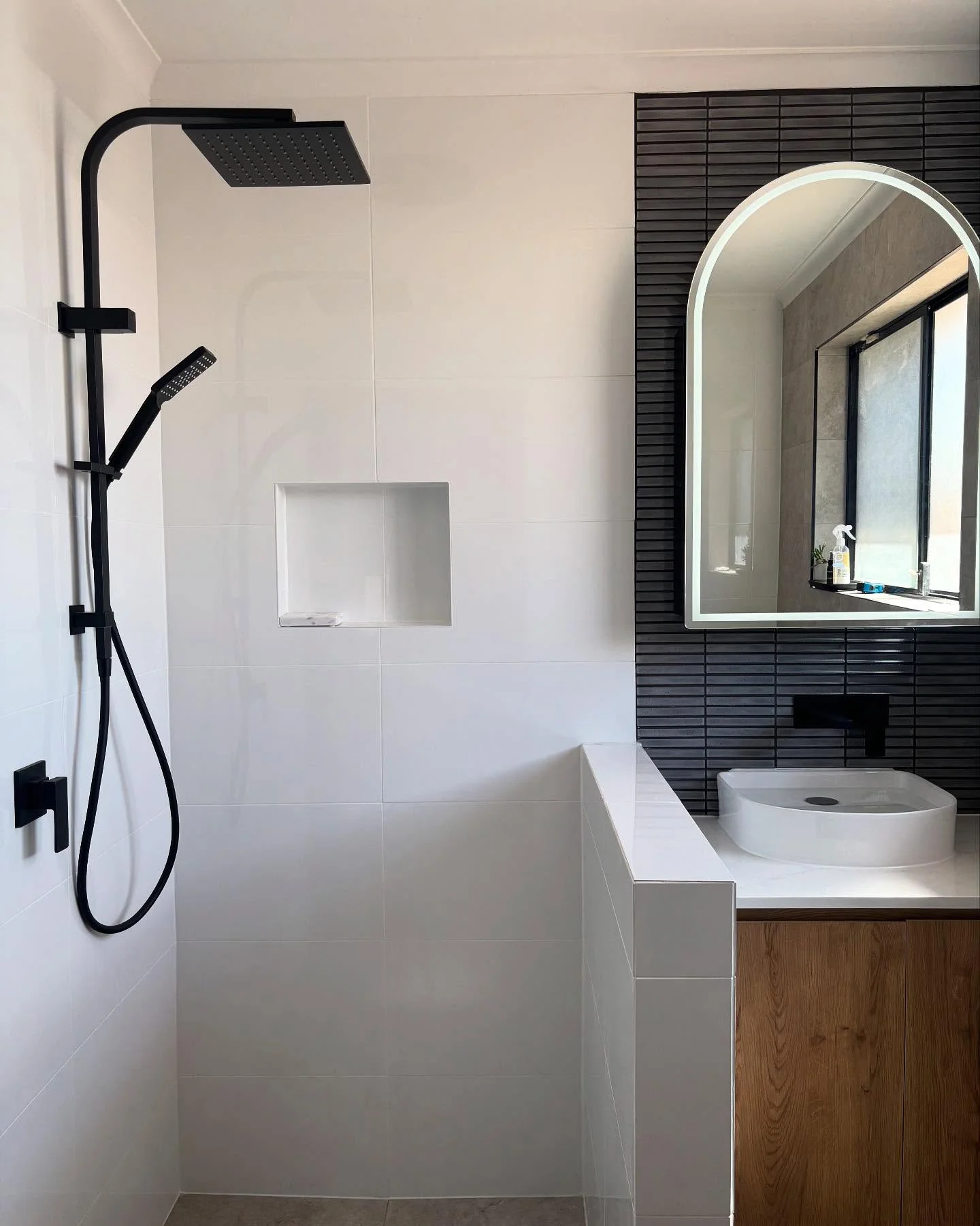 Completed R&J bathroom with black shower, timber vanity and arched mirror