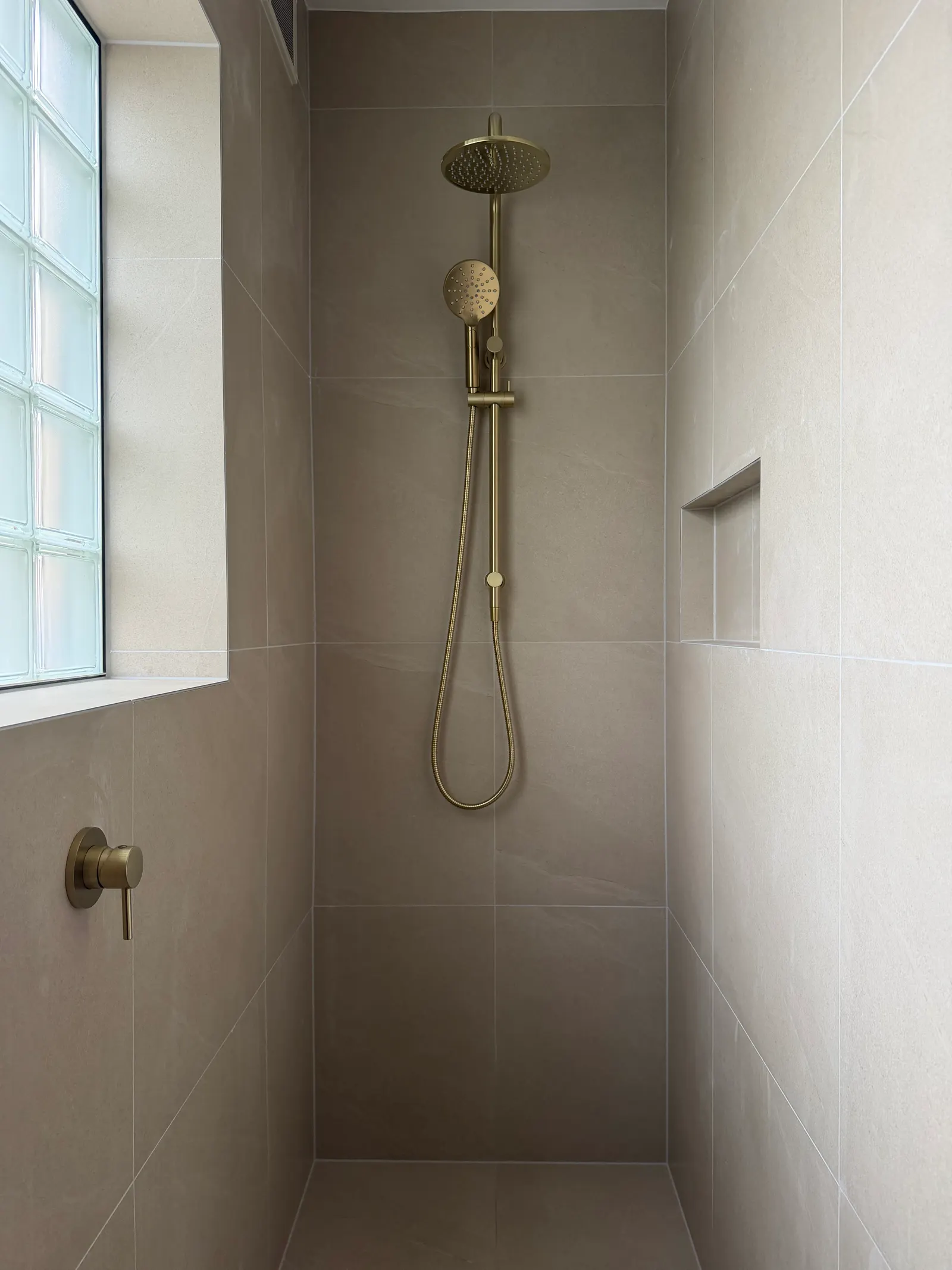 Brass shower fittings in a tiled walk-in shower