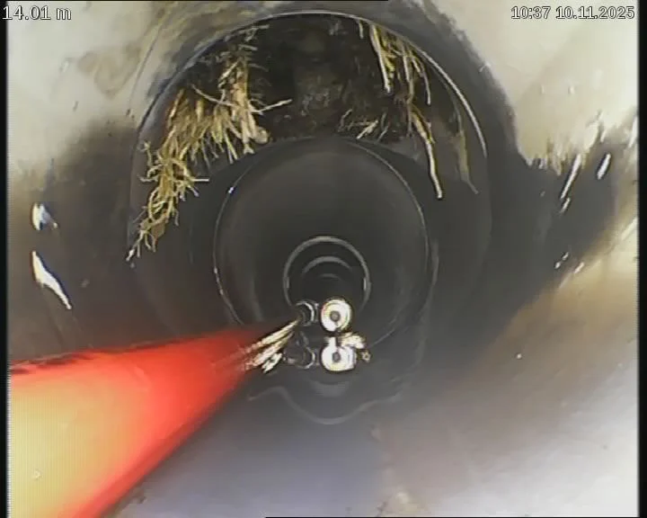 Drain camera view of tree roots in a pipe, with the hydrojet spraying