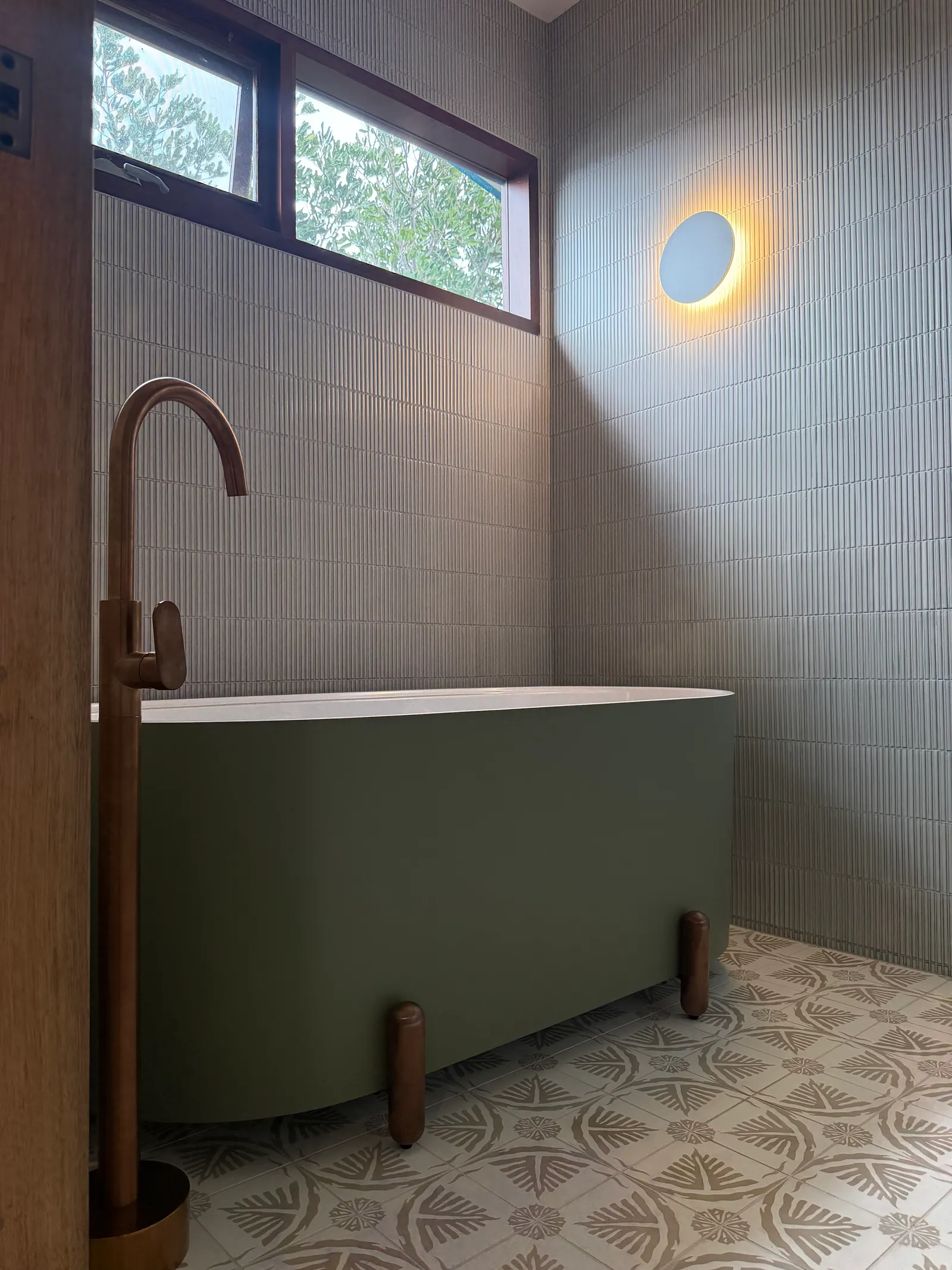 Green freestanding bath with a copper floor-mounted tap